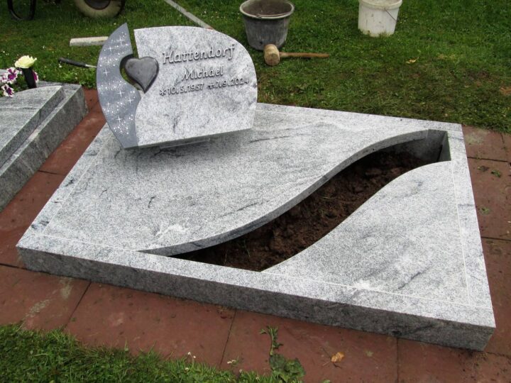 Grabmal Nr. 33: Urnengrabanlage aus hellem Granit mit Herzstein und geschwungenem Pflanzausschnitt