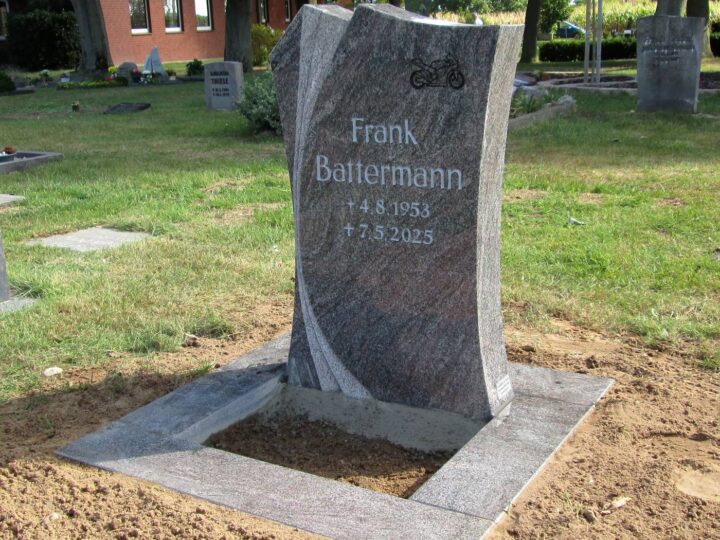 Grabmal Nr. 38: Geschwungener Grabstein aus Granit mit eingraviertem Motorrad auf einer Einfassungsplatte