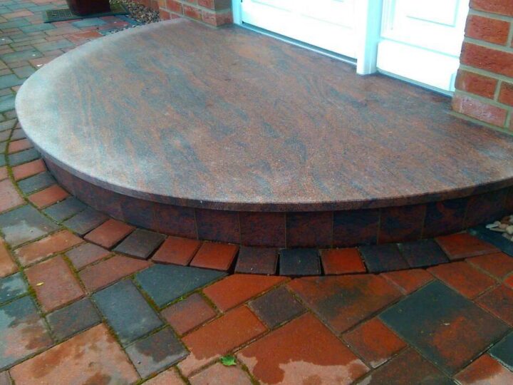 Halbrunde Podestplatte aus rötlichem Granit vor einer Haustür
